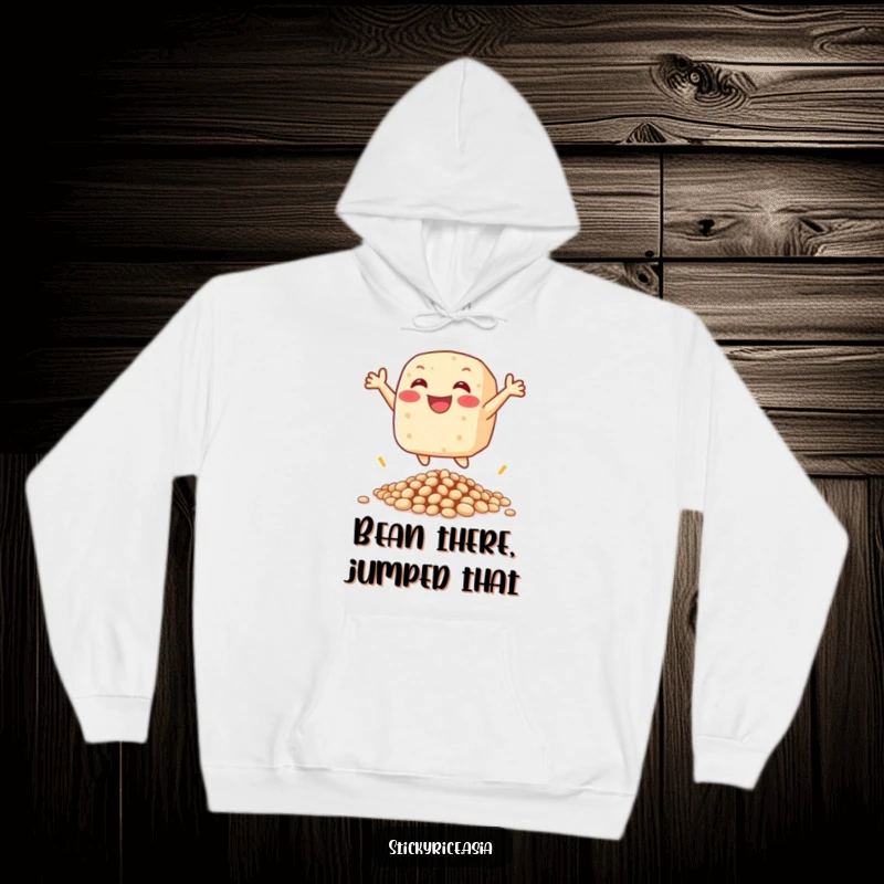 Funny hoodie with a happy sticky rice cake character leaping over beans, radiating warmth and playful energy.